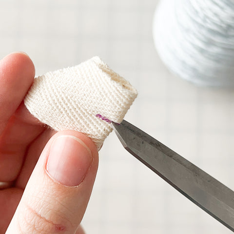 folded ribbon with scissors starting to cut the buttonhole slit open