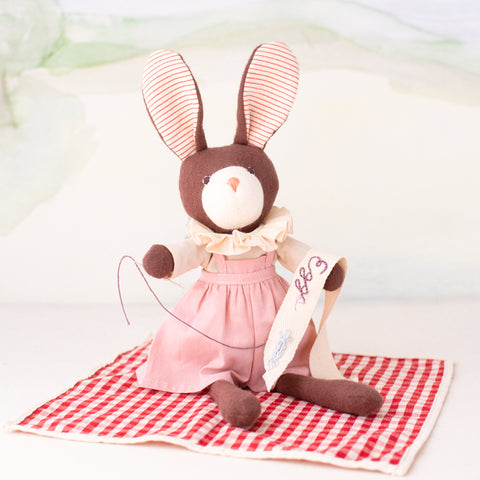 Zoe Rabbit sewing her egg sash on a picnic blanket in the Day Meadow