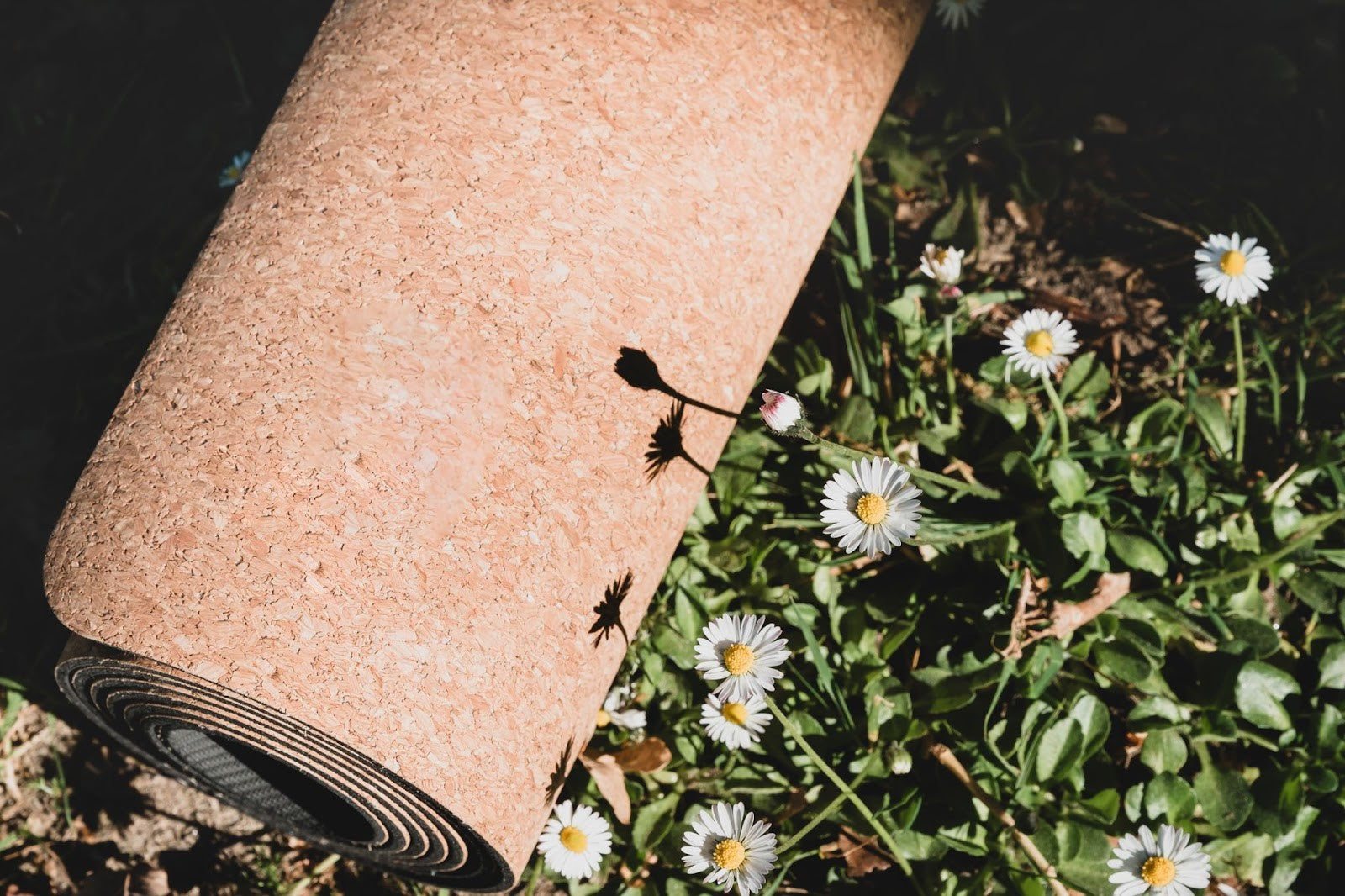 A cork yoga mat beside flowers