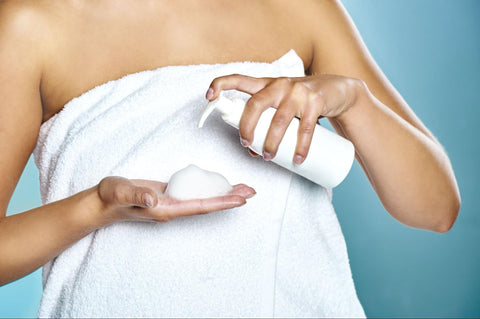 Cropped photo of a woman in a towel putting foam on her hands