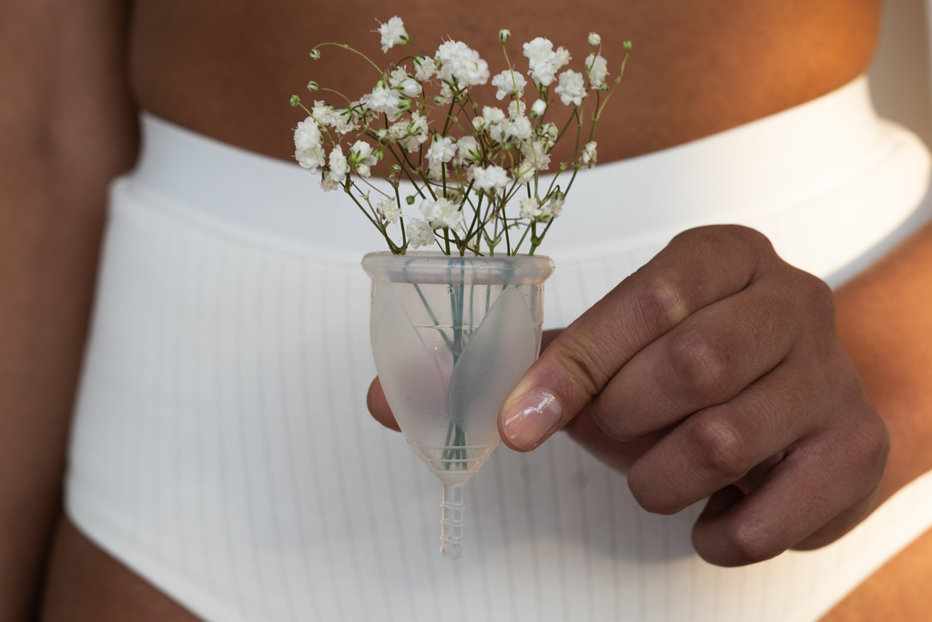 a woman holding a menstrual cup and wearing period underwear