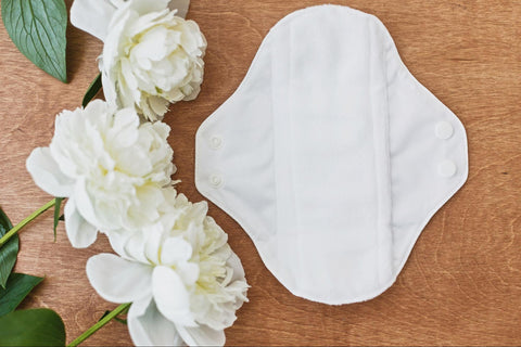 A reusable menstrual pad beside white flowers