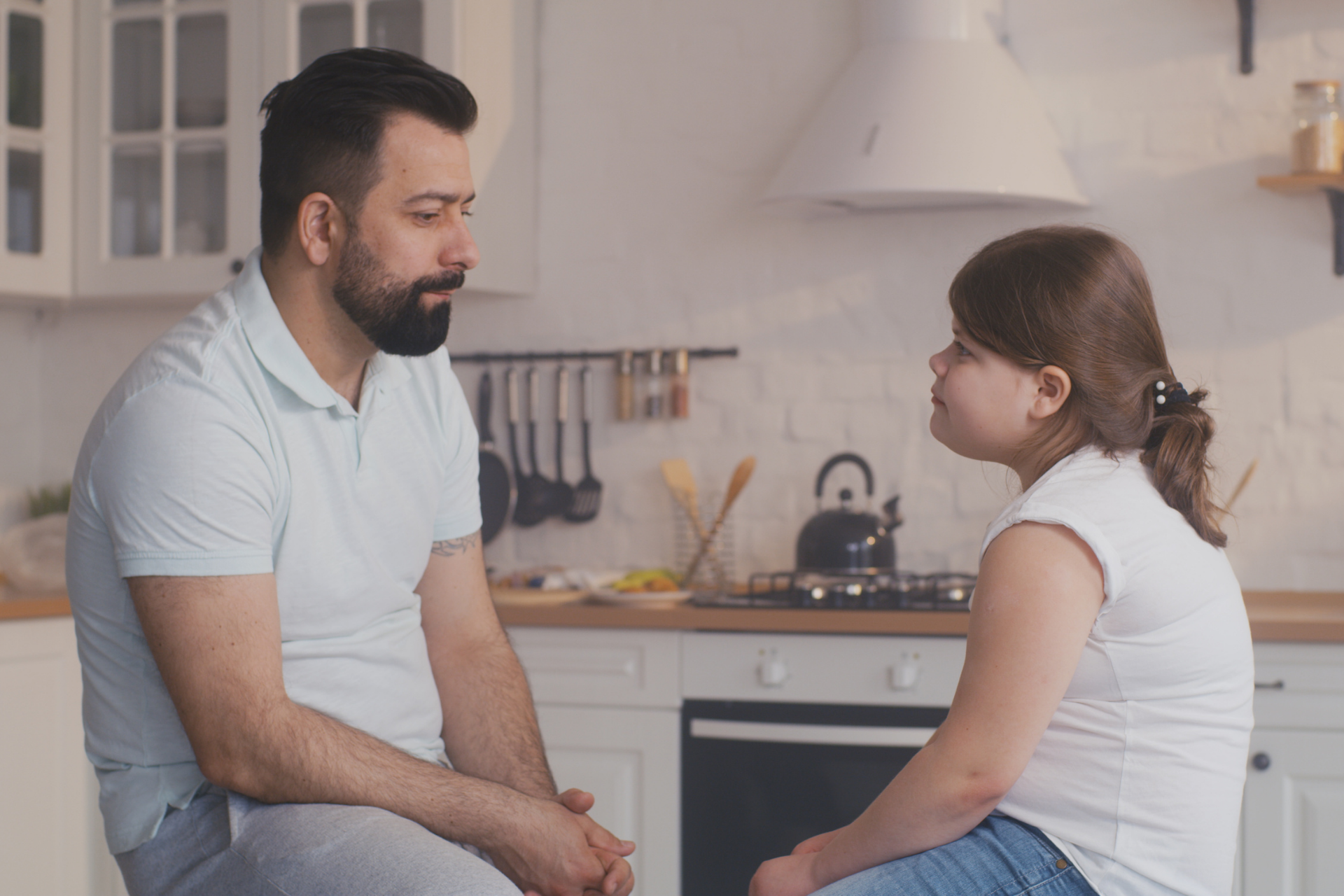 A dad practicing positive parenting by communicating with his daughter