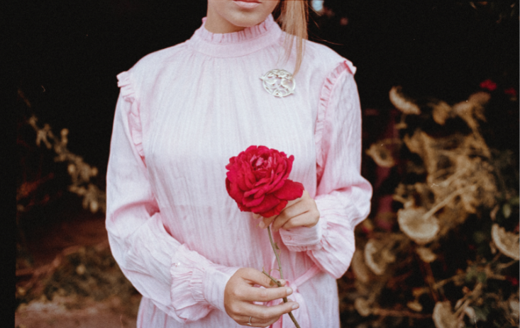 Cropped photo of a woman holding a red flower