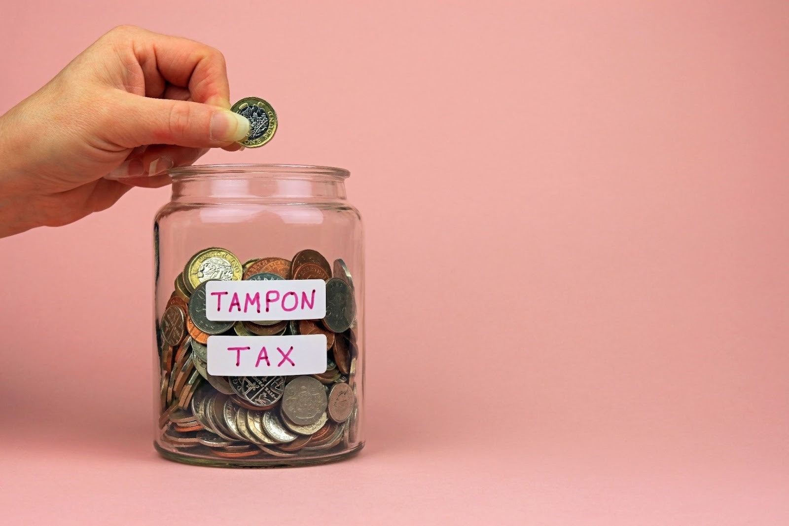 A jar of coins with a label on it that says “tampon tax”