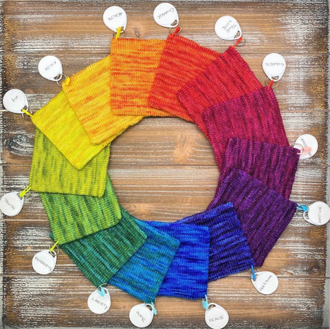 Picture shows 14 knitted swatches arranged in a circle by color, creating a rainbow color wheel.