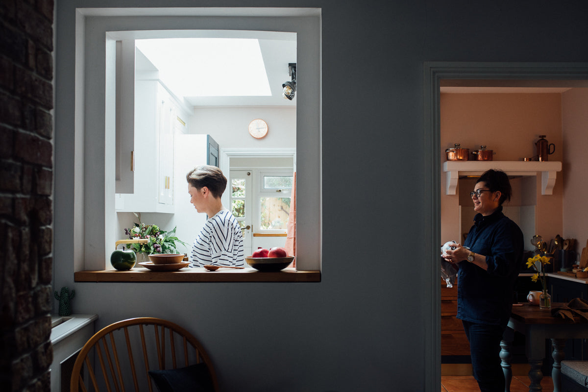 a woman is seen in a kitchen through an opening in the wall