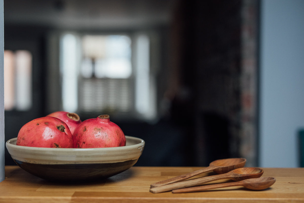 a black and beige serving bowl filled with pomegranates