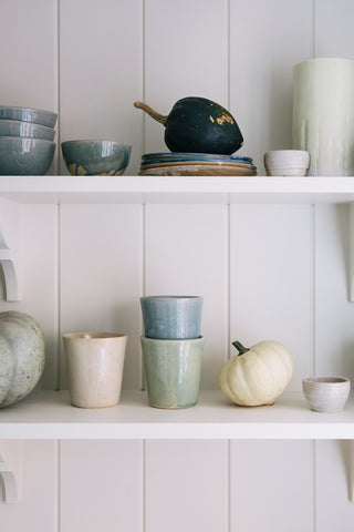 cream blue and green pots with pumpkins on a shelf