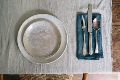 Cream stoneware dinner plates with a blue napkin