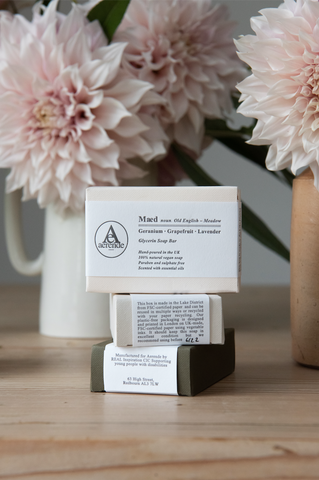 Three boxes of soap stacked up in front of peach-pink flowers