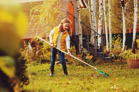 girl raking leaves outside for fall cleaning checklist