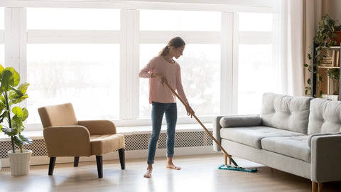 woman sweeping the floor using a monthly cleaning schedule as a guide