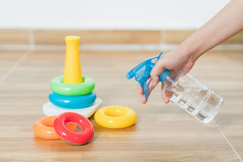 Woman Cleaning Baby Toys With Spray