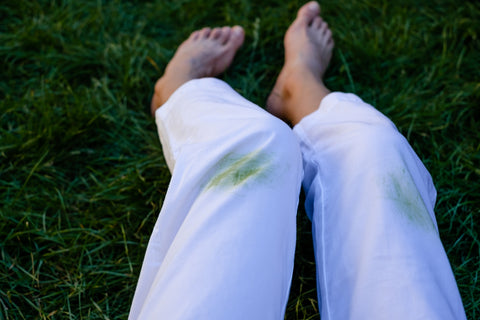 woman with grass stains on white jeans in her yard