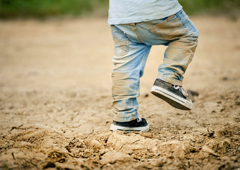 child playing in the dirt with dirt stains all over his pants