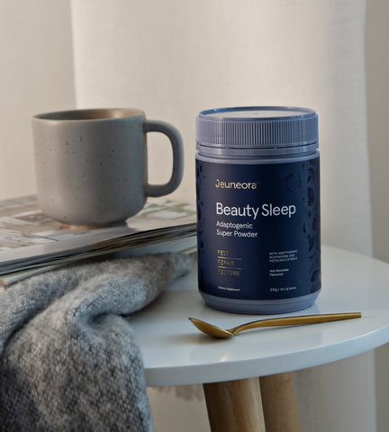 Jeuneora Beauty Sleep Adaptogenic Hot Chocolate powder sitting on bedside table in evening routine for sleep support.