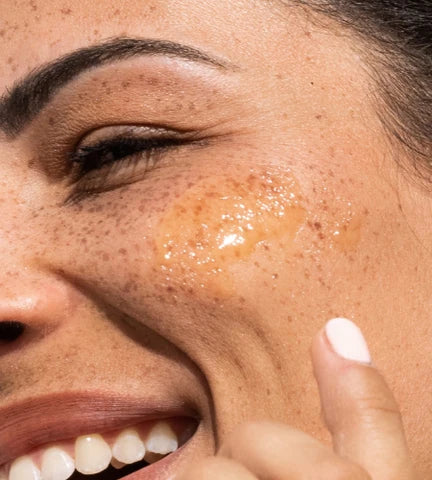 Woman applying orange Vitamin C serum onto skin in morning skincare routine