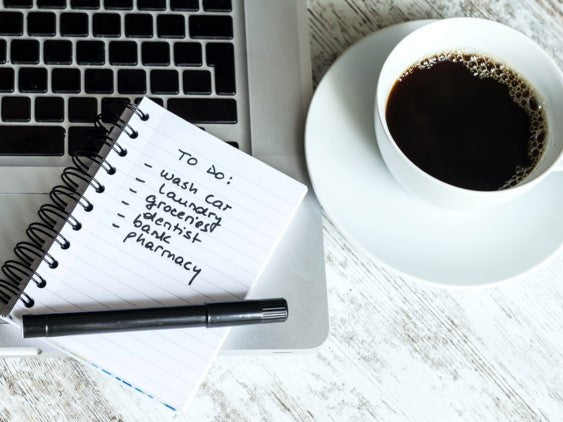 planner and pen on table beside coffee in cup 