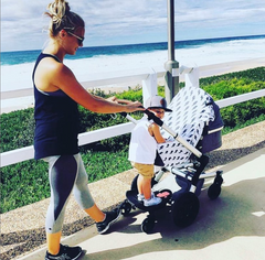 Woman in The Ten activewear pushing pram on seaside esplanade