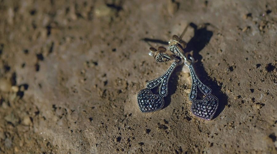 a pair of dangling marcasite silver earrings on the sand