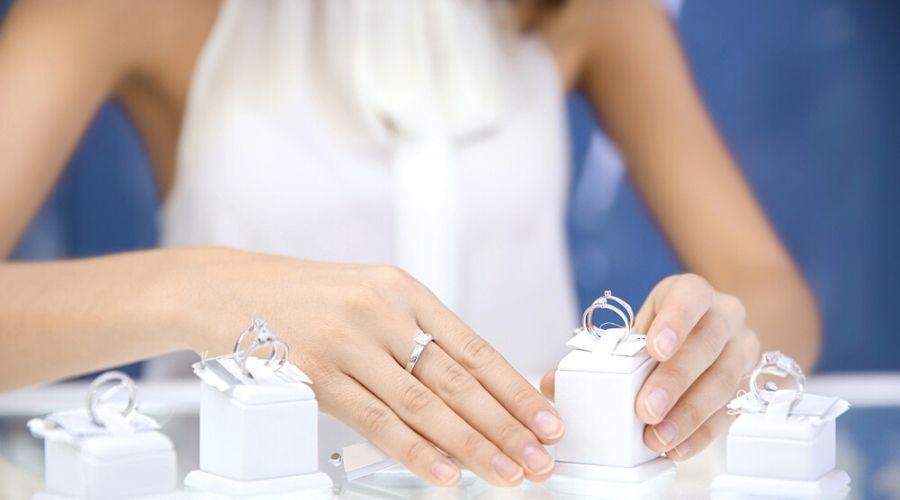 A woman choosing between several moissanite and cubic zirocnia rings