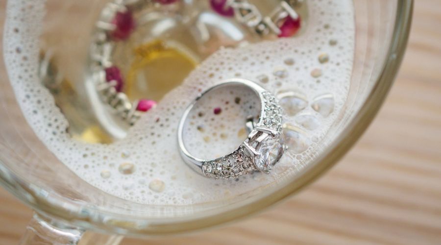 a sterling silver ring with gemstone in a cup with dish soap and water