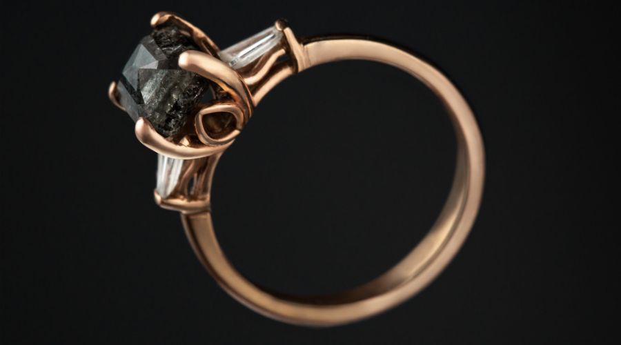 close up of a salt and pepper diamond engagement ring isolated on black background