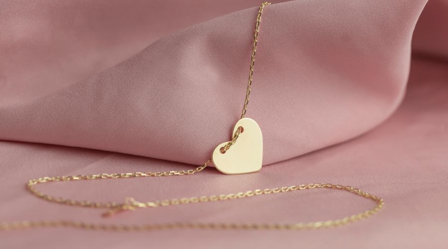 gold heart necklace on pink background