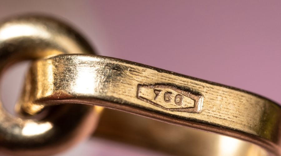 gold stamp 750 on a gold jewelry with scratches on the surface