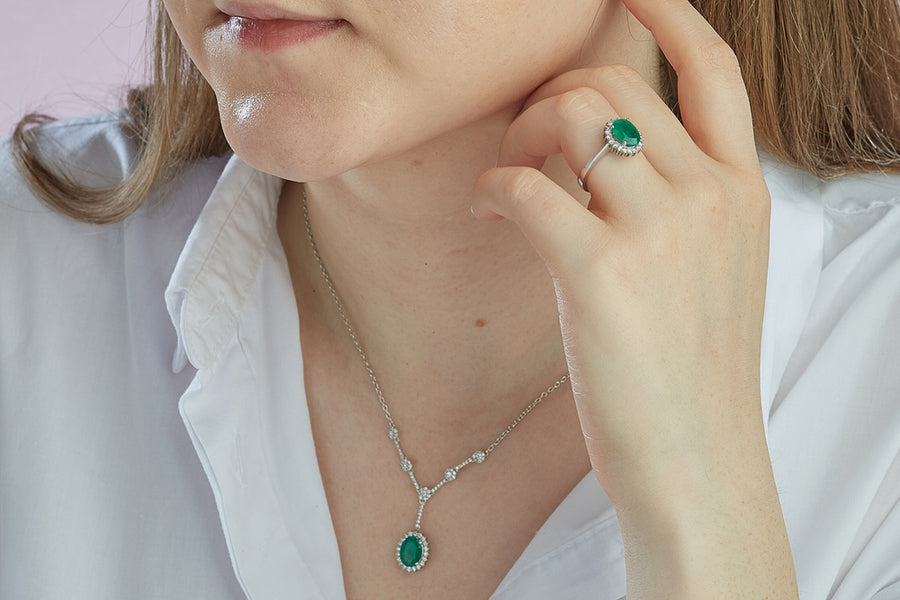 A woman wearing a green gemstone ring and necklace