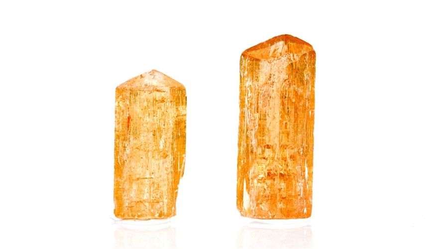 Two imperial topaz stones isolated against a white background