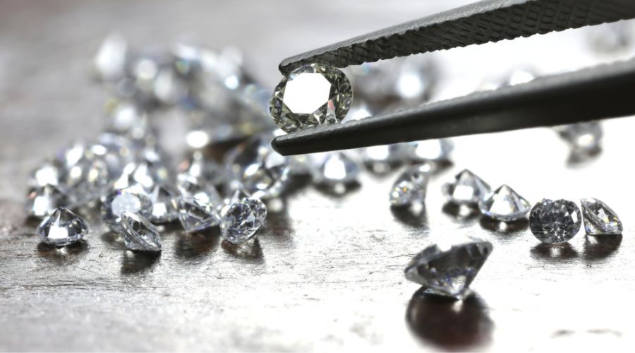 loose brilliant round cut diamonds and one held by a tweezer
