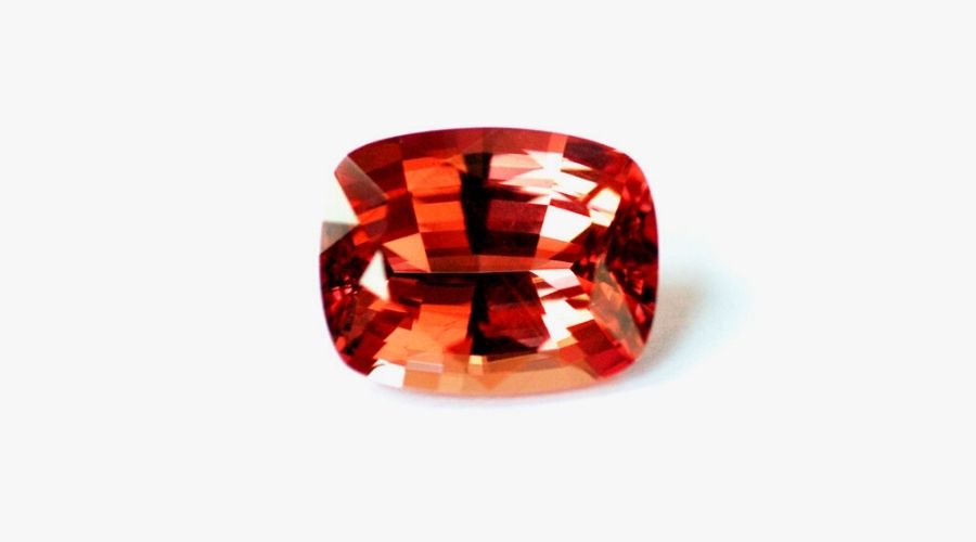 An orange spinel stone isolated against a white background