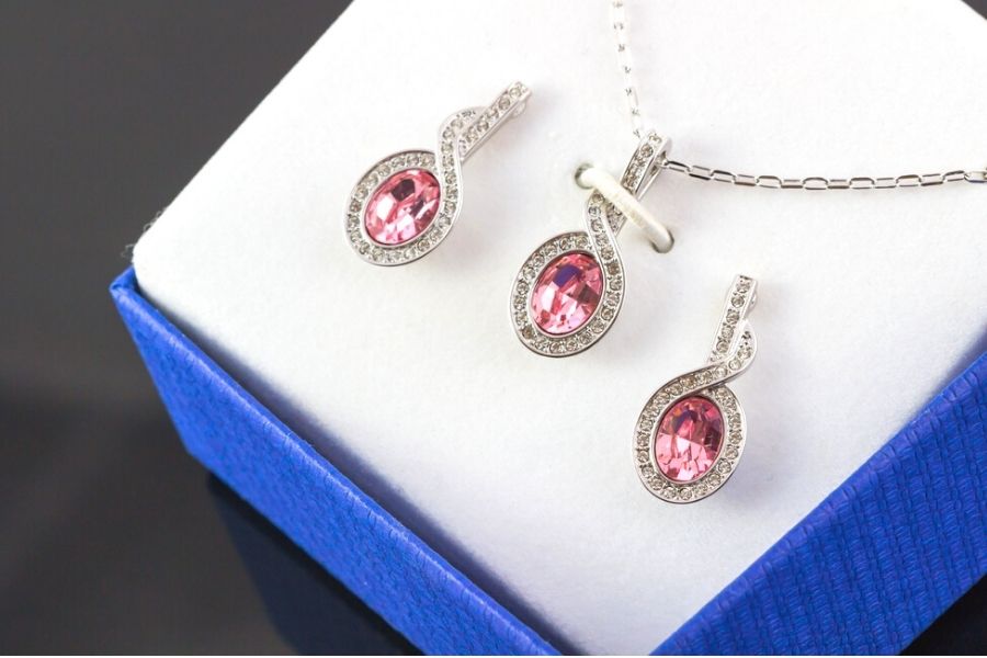 Pink gemstone necklace and earring set in a jewelry box.