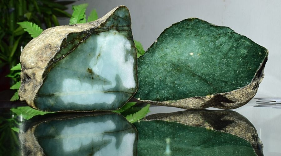 Raw jade pieces on a reflective surface