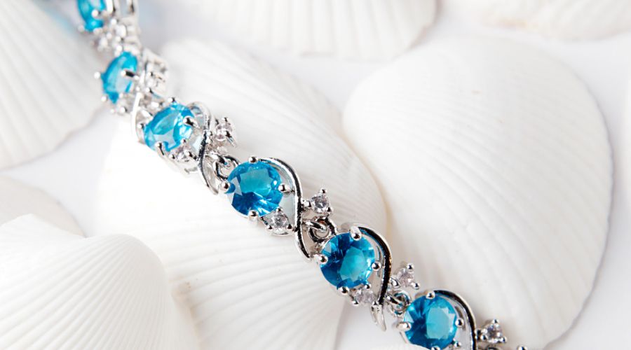 silver bracelet zircon blue stone with white shells background