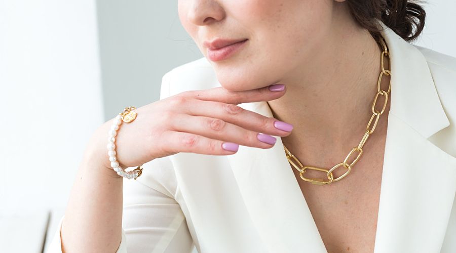 woman wearing a gold necklace and gold bracelet with pearls