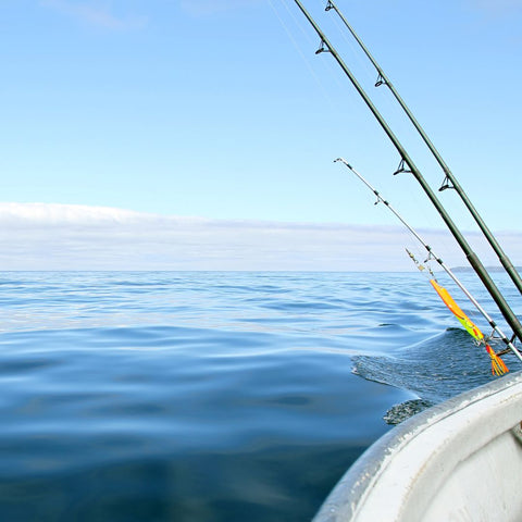 Fishing poles leaning over a boat on the ocean.