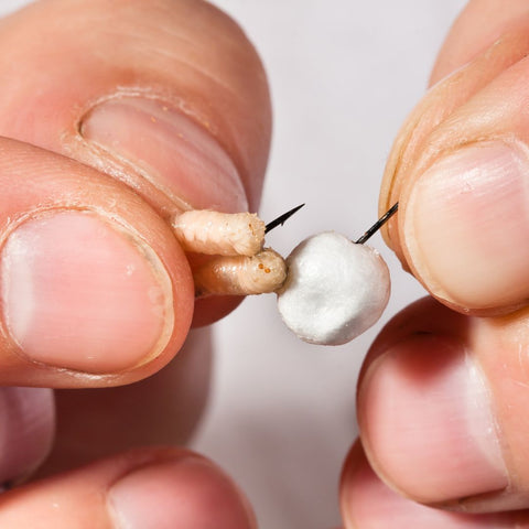 Person putting bait on a fishing hook