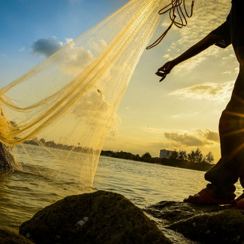 a person throwing a fishing net into the water