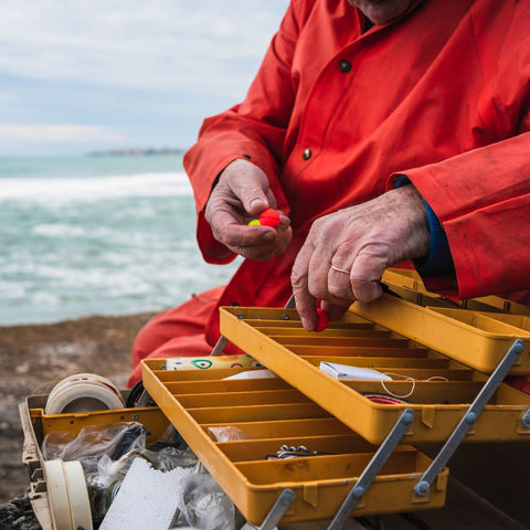 a man at the sea looking in an organized tackle box