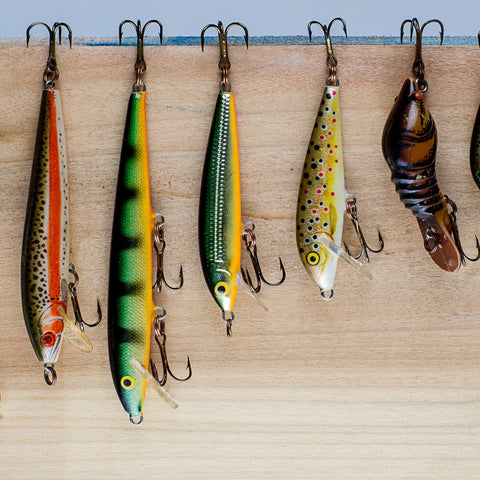 Fishing lures hanging on a wooden plank