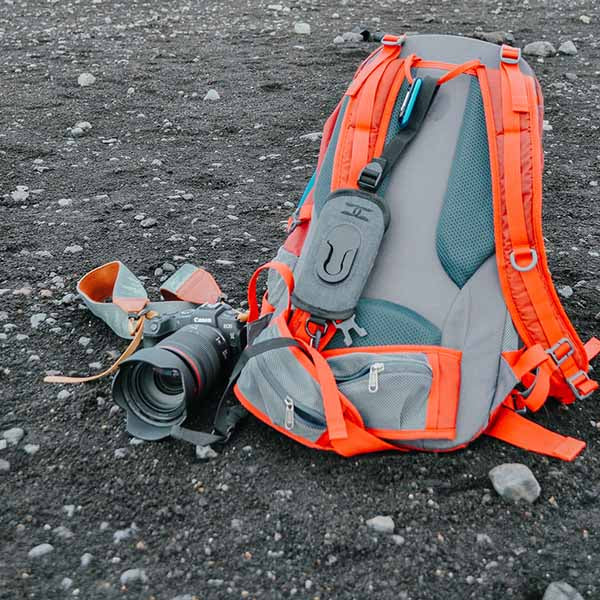 DSLR camera on the ground with a backpack and other photography gear for hiking