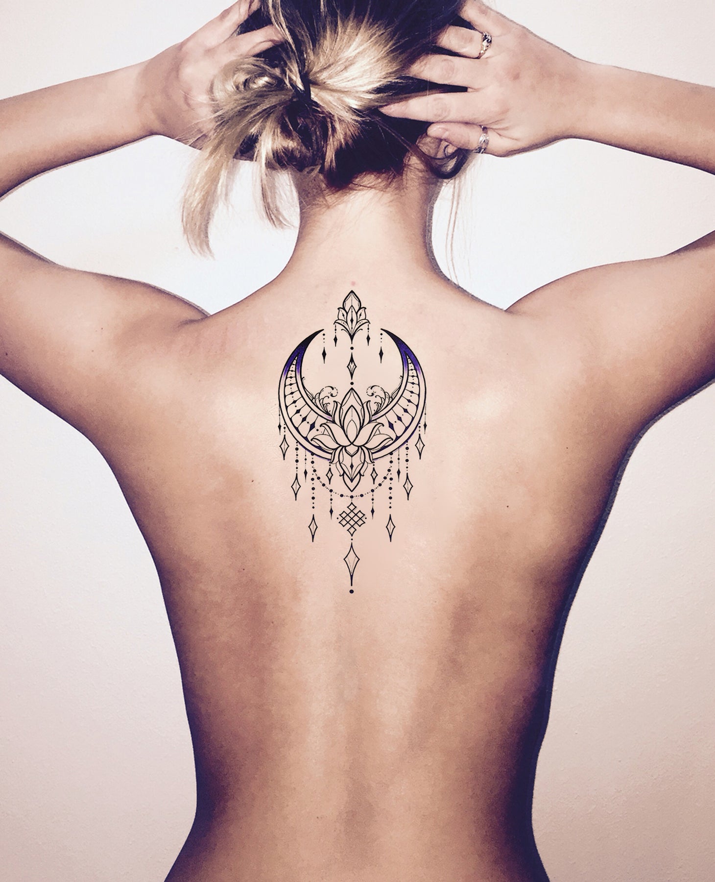 Black half sun and moon tattoo on upper back for women