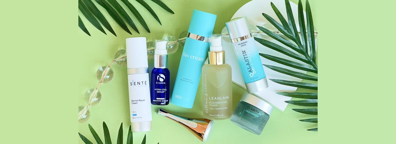 A group of skincare products against a pale green background with palm leaves