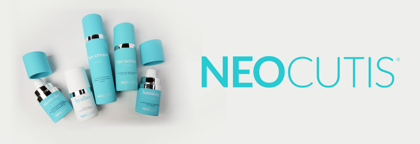Five Neocutis product bottles, some with their caps removed, laying on a pale grey background,with the turquoise-colored NEOCUTIS logo to the right.