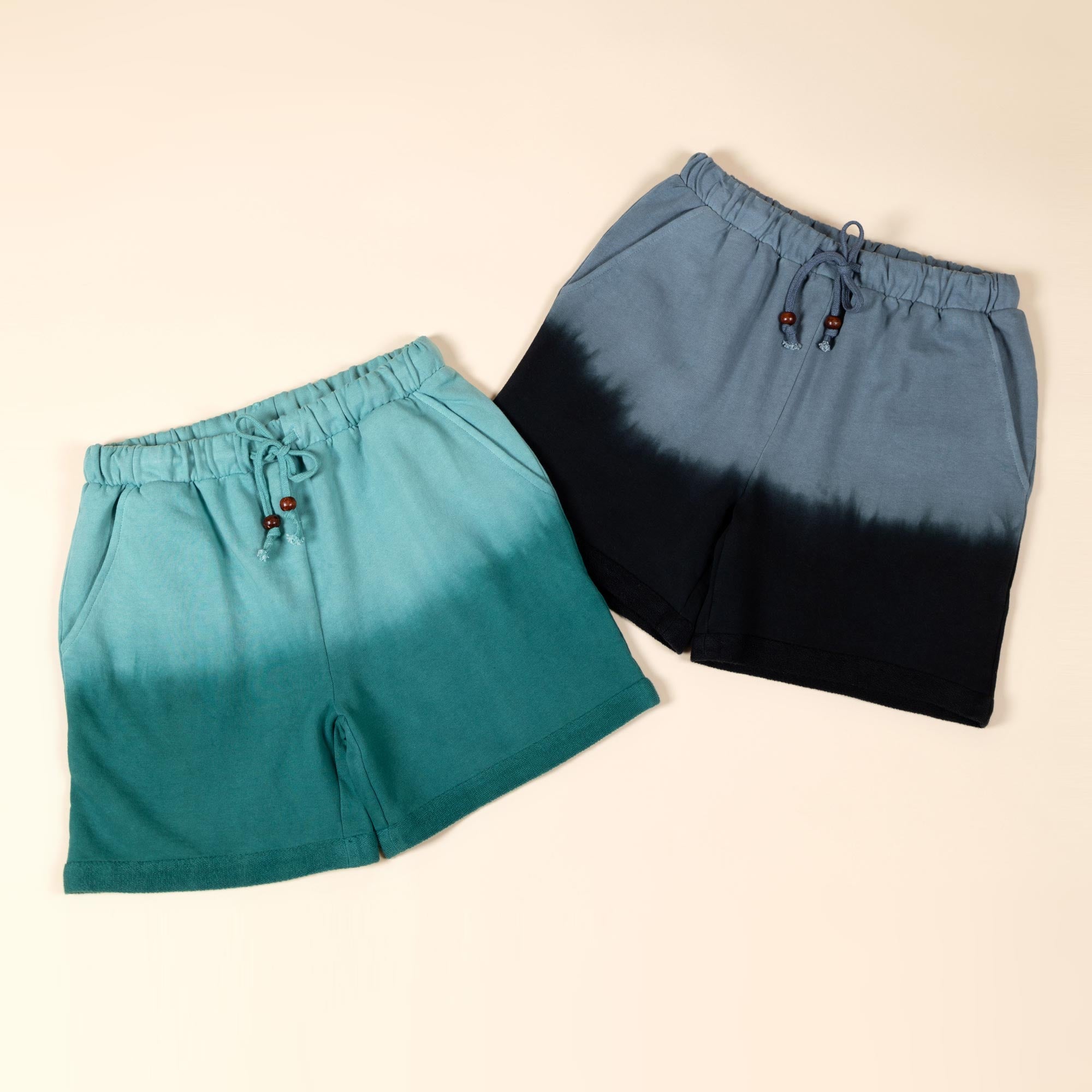 Three pairs of ombre dyed shorts lay on a clean background