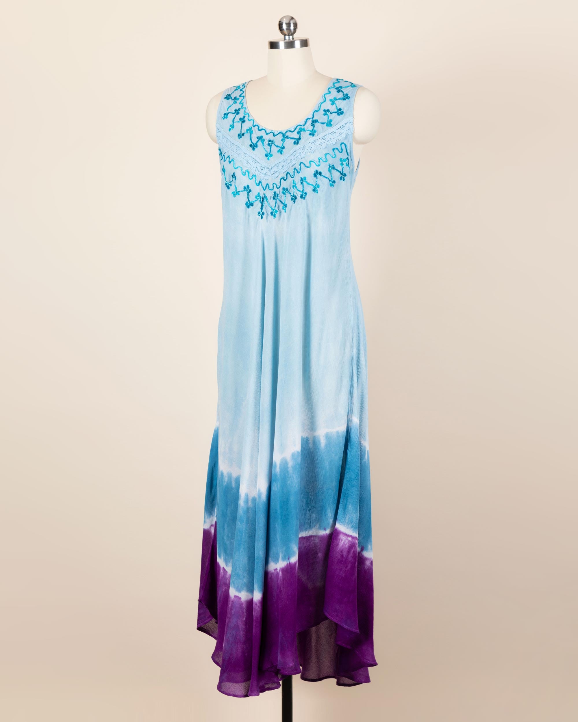 A dress featuring multi-colored tie-dye and stitched embelishments, hangs on a mannequin