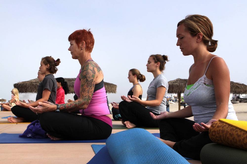 Women sit on mats during yoga class